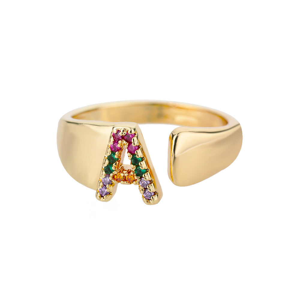 Anel com design vazado de 26 letras, cravejado com microzircônias coloridas e banhado a ouro 18K.